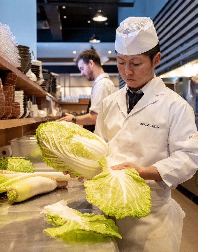 Shinichi Maeda preparing fresh greenery in-kitchen.
